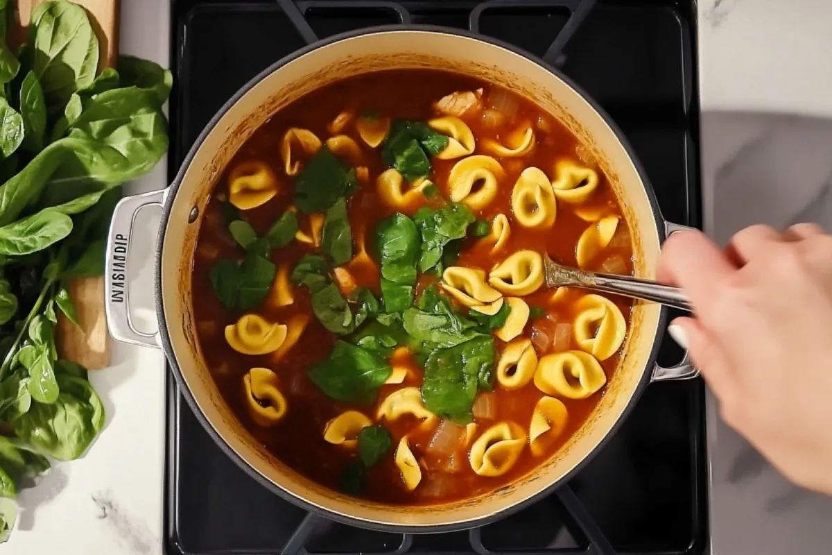 Simmering chicken tortellini soup in a pot on the stovetop. A glimpse into the cooking process of making this comforting dish.