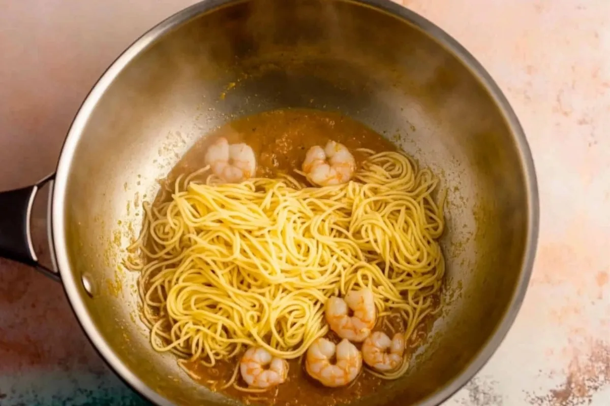 Cooking shrimp fra diavolo: adding shrimp to spicy tomato sauce in a skillet, steam rising. Homemade.