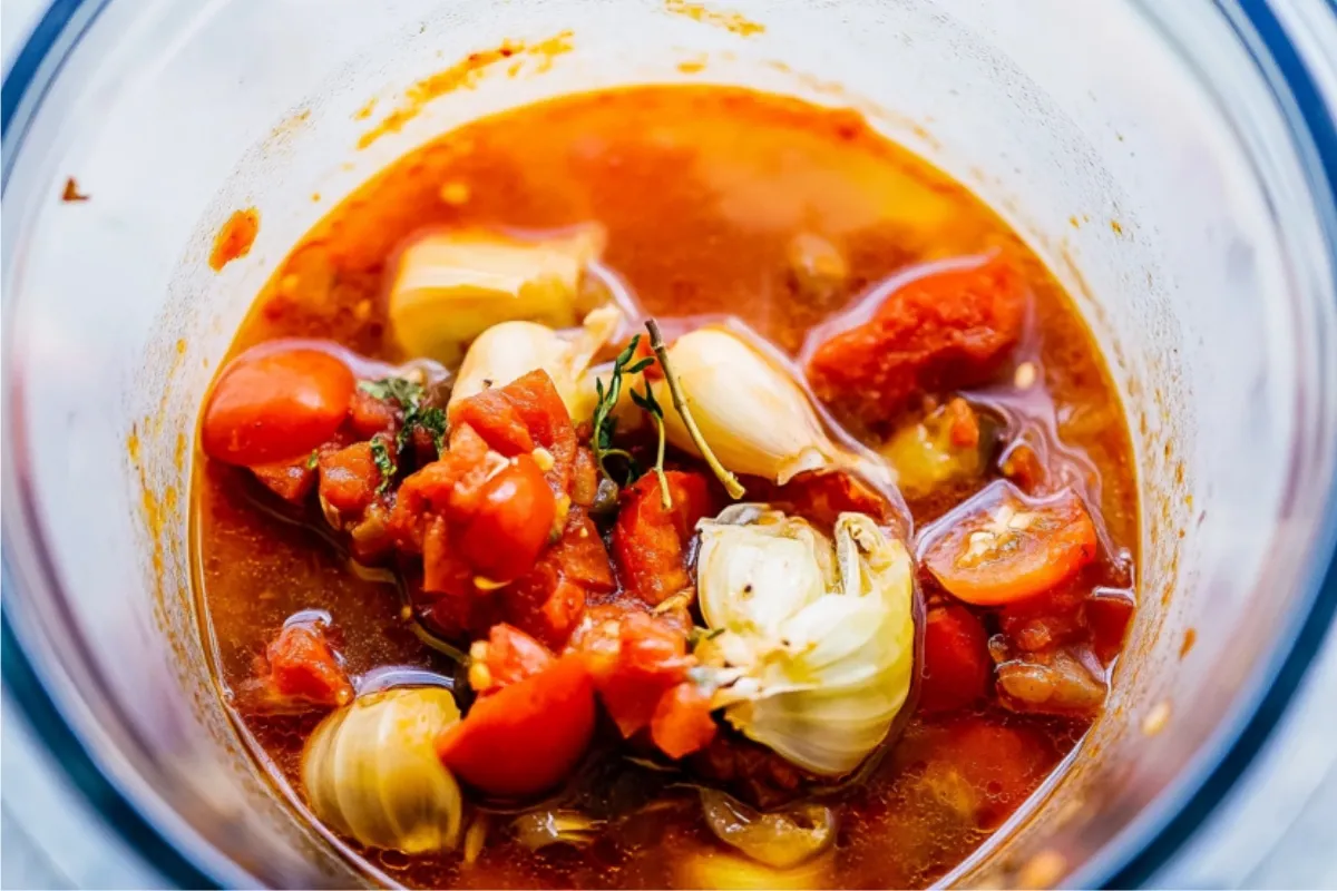 Pot of tomato bisque recipe simmering with tomatoes and herbs. Fresh ingredients.